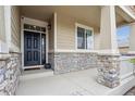 Inviting front porch with stone accents, a security camera, and stylish lighting at 15524 E 115Th Ave, Commerce City, CO 80022