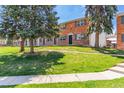 Brick townhouse with a large grassy front yard and mature trees providing shade at 13977 E Bails Pl, Aurora, CO 80012