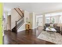 Bright living room featuring hardwood floors, a staircase, and an open layout flowing into other living spaces at 2857 Xanthia Ct, Denver, CO 80238