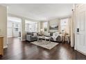 Comfortable living room showcasing dark hardwood floors, neutral decor, and ample natural light through large windows at 2857 Xanthia Ct, Denver, CO 80238
