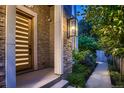 Striking modern front door with stone facade and manicured landscaping under evening lights at 2821 E Cedar Ave # 14, Denver, CO 80209