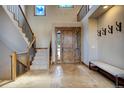 Spacious foyer with a wooden staircase, tiled flooring, a cozy bench, and a decorative wooden front door at 11405 Conifer Ridge Dr, Conifer, CO 80433