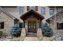 Charming entryway with stone pillars and a natural wood door, complemented by two small evergreen trees at 11405 Conifer Ridge Dr, Conifer, CO 80433