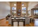 Elegant living room with a stone fireplace, hardwood floors, and large windows showcasing the outdoor scenery at 11405 Conifer Ridge Dr, Conifer, CO 80433