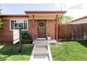 Charming brick home features a covered entry with a wreath-adorned door and landscaped lawn at 5190 E Asbury Ave, Denver, CO 80222