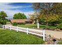 Charming home with a manicured lawn, mature tree, and a white fence lining the property at 2117 Stonehenge Cir, Lafayette, CO 80026