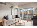 Bright living room with a barn door, hardwood floors, a comfortable sofa and a balcony with city views at 1475 Delgany St # 306, Denver, CO 80202