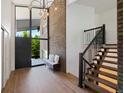 Bright foyer featuring wood floors, modern chandelier, brick accent wall, and staircase to the upper level at 5265 W Quarles Dr, Littleton, CO 80128