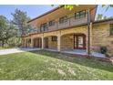Two-story brick house with balcony and covered entryway, featuring attached garages and a well-manicured lawn at 12196 W Belleview Dr, Littleton, CO 80127
