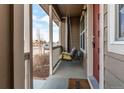 Charming covered porch with a swing, offering a relaxing outdoor space and lovely view and an inviting 'welcome' mat at 256 Ash St, Bennett, CO 80102