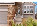Inviting front entrance with stone accents, landscaping, and an arched window above the front door at 8635 Cresthill Ln, Highlands Ranch, CO 80130