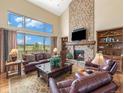 Elegant living room boasts a stone fireplace, vaulted ceilings, and a wall of windows with beautiful pastoral views at 1660 Prominence Cir, Elizabeth, CO 80107