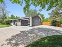 View of the home's exterior showcasing a large driveway, modern garage door, and well-maintained landscaping at 1333 W Peakview Ave, Littleton, CO 80120