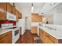 Bright kitchen featuring wood cabinets, white appliances, and a modern stove at 11565 Decatur St # 7D, Denver, CO 80234
