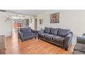 Bright living room featuring hardwood floors, two sofas, an armchair, and decorative wall art at 15627 E 51St Dr, Denver, CO 80239
