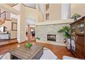 Cozy living room featuring a stone fireplace, high ceilings, hardwood floors, and seamless access to other areas of the home at 4 White Fir Ct, Littleton, CO 80127