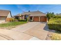 A beautifully landscaped yard and wide driveway leading to a two-car garage enhance this home's curb appeal at 5448 S Swadley Ct, Littleton, CO 80127
