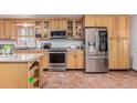 Well-equipped kitchen featuring stainless steel appliances, ample storage, tile flooring, and natural wood cabinets at 9400 W Burgundy Ave, Littleton, CO 80123