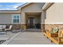 Charming front porch with seating, stone accents, and inviting entrance to the home at 16482 Ledyard S Rd, Platteville, CO 80651