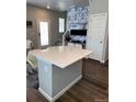 Open living area featuring an island bar with quartz countertop, designer wallpaper, and laminate flooring at 1353 Reynolds St # 5A, Fort Lupton, CO 80621