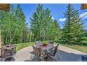 Outdoor patio area with a table, chairs, and fireplace overlooking a wooded landscape at 153 Gold Run Trl, Idaho Springs, CO 80452