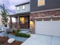 Front elevation with stone and siding, covered porch, manicured landscaping and two-car garage at 1803 S Coolidge St, Aurora, CO 80018