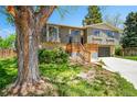 Split-level home featuring a newly built deck and attached two-car garage surrounded by mature trees at 7448 W Geddes Pl, Littleton, CO 80128