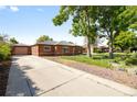 Brick exterior home with a private driveway, beautiful trees, and lush landscaping at 1560 Pueblo Ct, Thornton, CO 80229