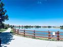 Scenic community lake view with a walking path and wooden fence at 9377 Longstone Dr, Parker, CO 80134