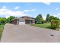 An exterior view of a brick home with a long driveway and well maintained lawn at 8333 Depew Way, Arvada, CO 80003