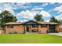 Charming brick ranch home with a well-maintained lawn, black trim, and a cozy front porch at 7256 S Broadway, Centennial, CO 80122