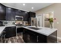 Modern kitchen with stainless steel appliances, dark cabinets, mosaic backsplash, and a center island at 139 N Prairie Falcon Pkwy, Brighton, CO 80601