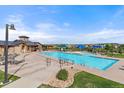 Community pool and clubhouse with lounge chairs, tables and umbrellas, and lush landscaping at 14589 Hagus Pl, Parker, CO 80134
