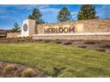 Stone community sign for Heirloom with manicured landscaping and a bright blue sky backdrop at 14589 Hagus Pl, Parker, CO 80134
