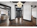 Elegant foyer showcasing dark wood floors, paneled trim and a modern chandelier at 46692 Silver Fir St, Parker, CO 80138