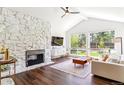 Cozy living room features a stone fireplace, wood floors, and large windows showcasing the backyard at 6488 S Heritage E Pl, Centennial, CO 80111