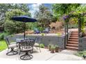 Outdoor dining area featuring a table and chairs under an umbrella, with a firepit and lush greenery at 8291 S Krameria Way, Centennial, CO 80112