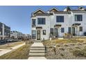 Modern townhome exterior featuring white siding, black trim, and a welcoming front entrance with a concrete walkway at 1301 Osceola St, Denver, CO 80204