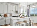 Stylish kitchen with white cabinets, marble backsplash, and an island with seating for three at 1601 Mariah Ln, Erie, CO 80516