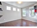 Inviting room with hardwood floors, bright natural light from three windows, and minimalist decor at 15955 E Otero Cir, Centennial, CO 80112