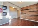 Open room with hardwood floors, accent wall with shelving, and modern lighting at 15955 E Otero Cir, Centennial, CO 80112