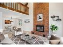 Bright living room with a brick fireplace, high ceiling, and loft overlook at 1206 E Phillips Pl, Littleton, CO 80122