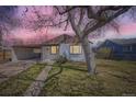 Exterior of a light colored one-story home with a driveway and large tree, in front of a pink sky at 1280 S Quitman St, Denver, CO 80219