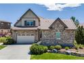 Charming two-story home boasts a stone facade, three-car garage, and inviting curb appeal on a sunny day at 10590 Soulmark Way, Highlands Ranch, CO 80126