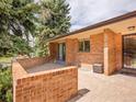 Brick patio features sliding glass door, entry door with security door, and brick privacy wall at 2615 Oak Dr # 5, Lakewood, CO 80215