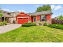 Inviting front exterior showcasing the home's red siding, brick foundation, and landscaped front yard at 5577 Jasper St, Denver, CO 80239