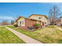 Well-maintained home with brick and siding exterior, lush lawn, and convenient sidewalk access at 3355 S Flower St # 107, Lakewood, CO 80227