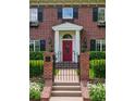 Elegant red front door framed by white columns, complemented by a black iron gate and manicured hedges at 6300 E 17Th Avenue Pkwy, Denver, CO 80220