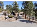 Scenic driveway leading to a charming mountain home surrounded by mature trees and natural landscape at 4948 Cameyo Rd, Indian Hills, CO 80454