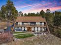 Two-story home with large windows, outdoor entertaining space, and manicured landscaping at 4948 Cameyo Rd, Indian Hills, CO 80454